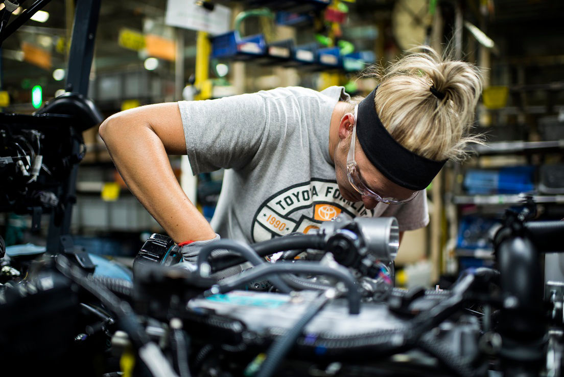 Female technician working on forklift machinery.