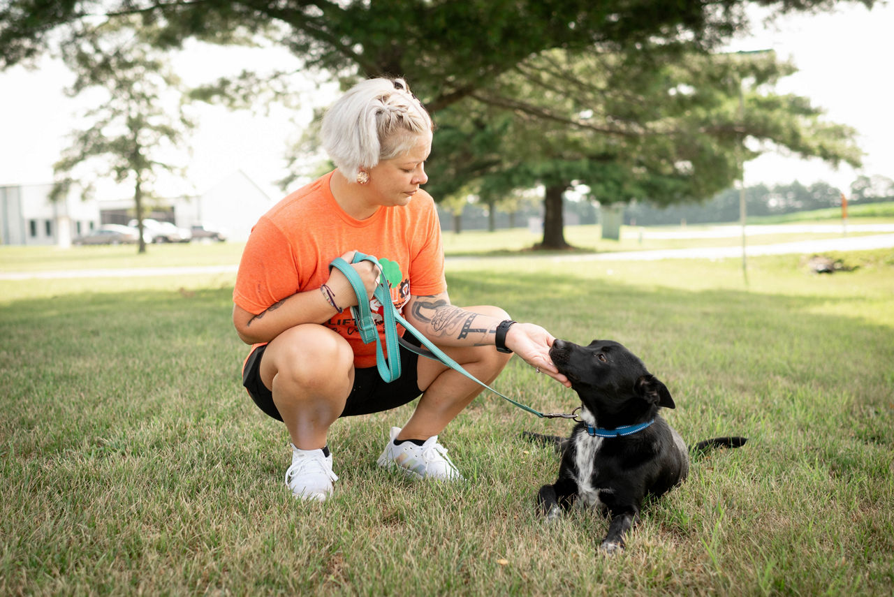 tmh employee pets dog in grass for lift the community day 